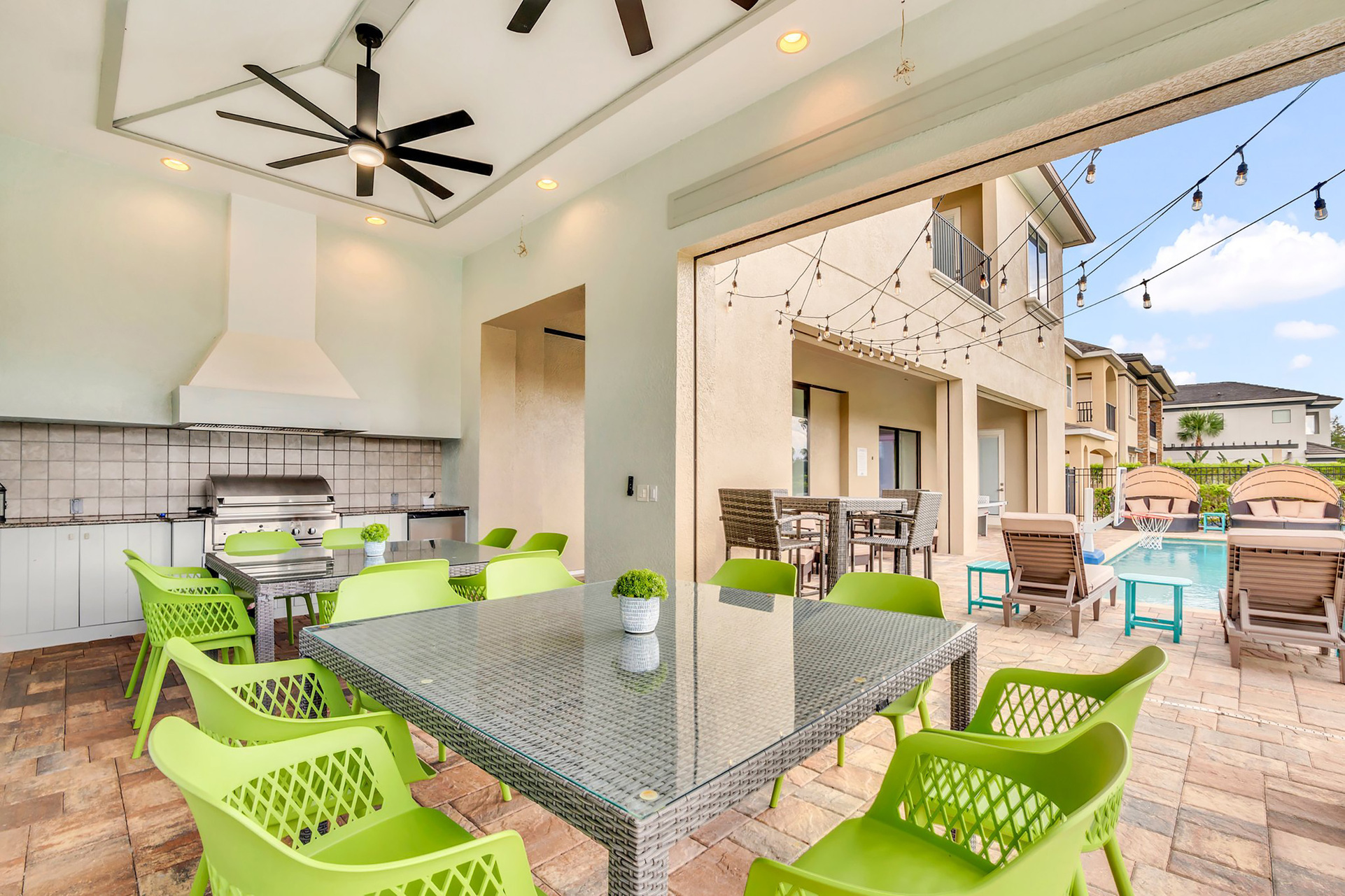 Dine al fresco in the summer kitchen with built-in BBQ, outside dining table, and TVs