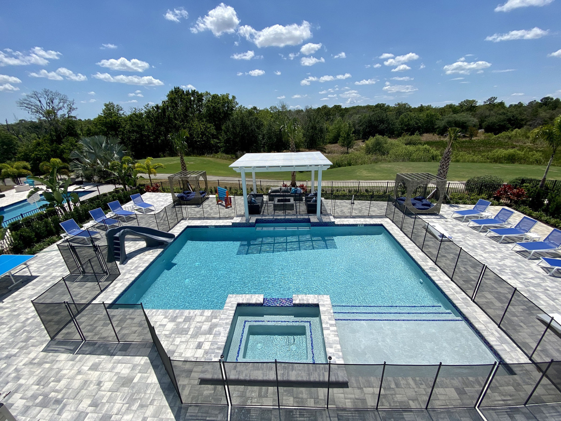 The patio offers a private pool with a spillover spa, a ping pong table, a foosball table, plenty of comfortable seating to choose from, and a summer kitchen