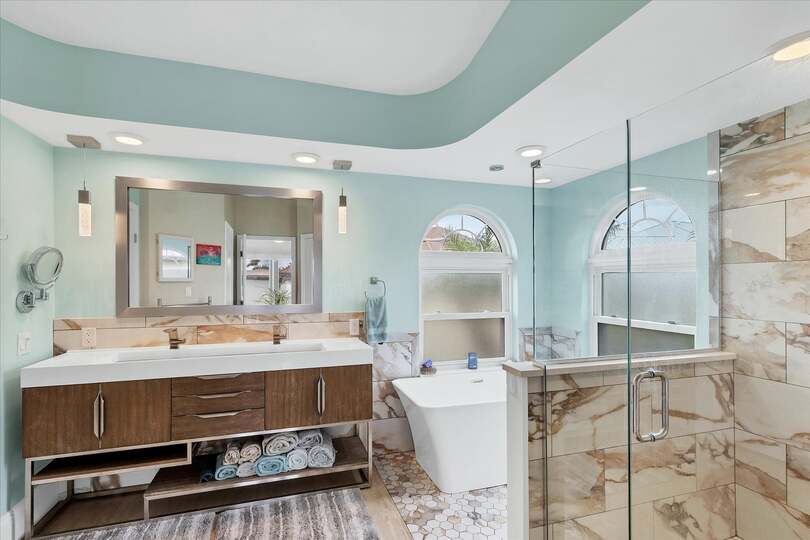 Primary attached bathroom with large walk-in shower, soaking tub, and double vanities
