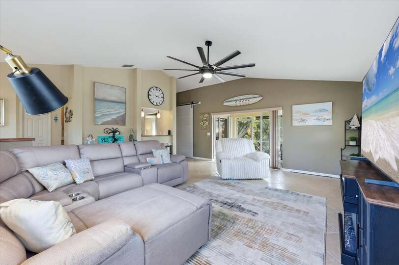 Living room features lots of comfy seating, patio access, and 85-inch Smart TV