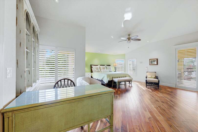 Huge primary bedroom with king bed, lanai acces, attached bathroom, desk & chair, and 55-inch Smart TV